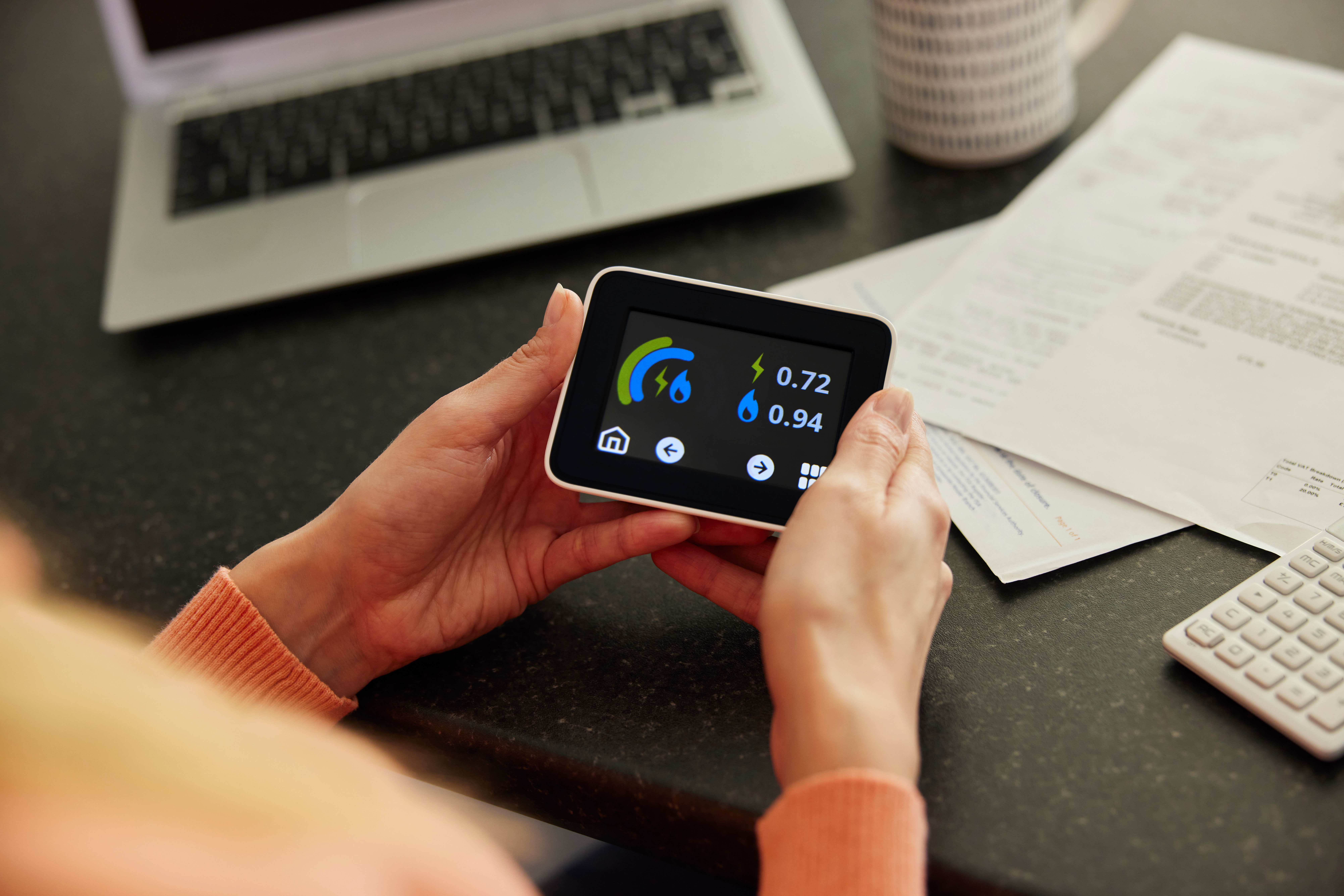 Close Up Of Woman Holding Smart Energy Meter In Kitchen Measuring