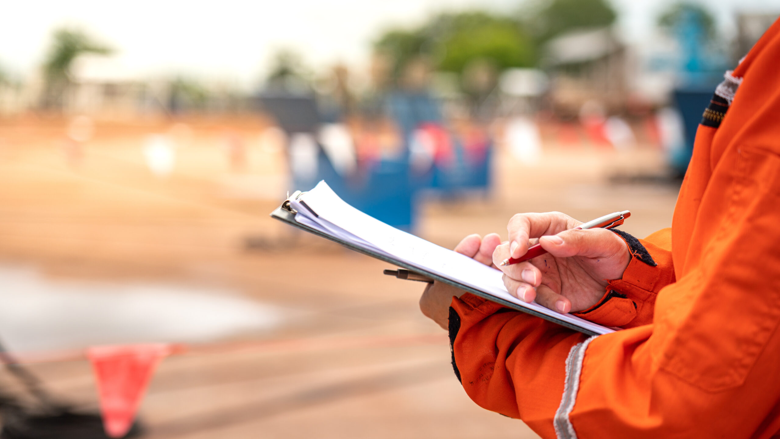 man in orange clothings arm holding checklist for site audit