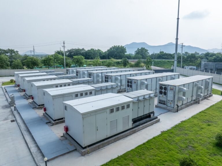 battery storage power station surrounded by grass and trees in distance