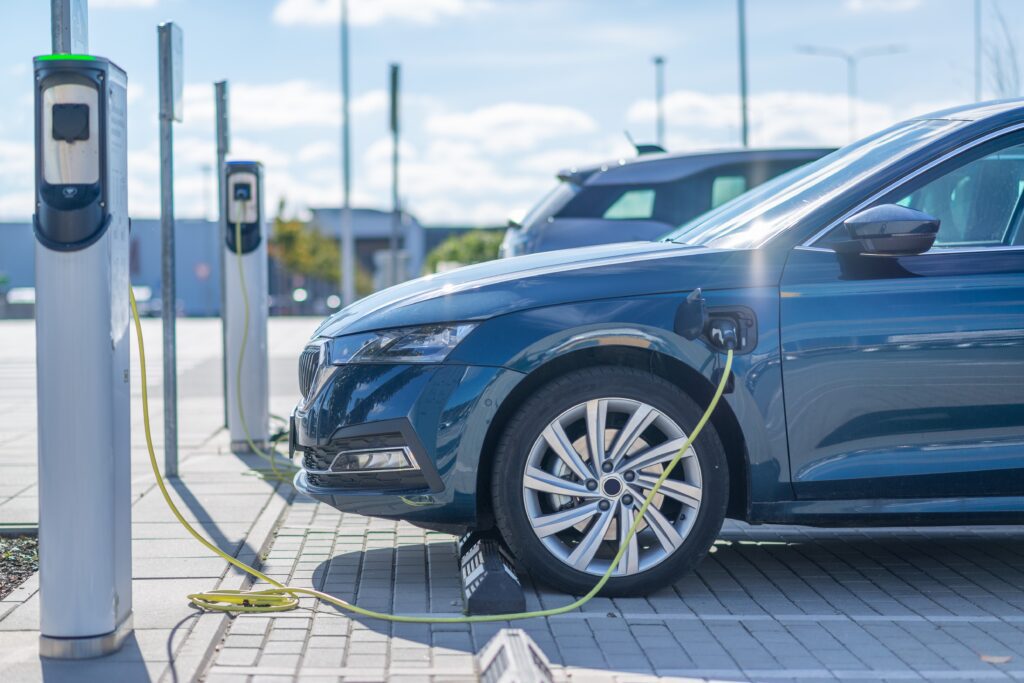 Electric car charging at an ev charger station in car park representing depot charging scheme