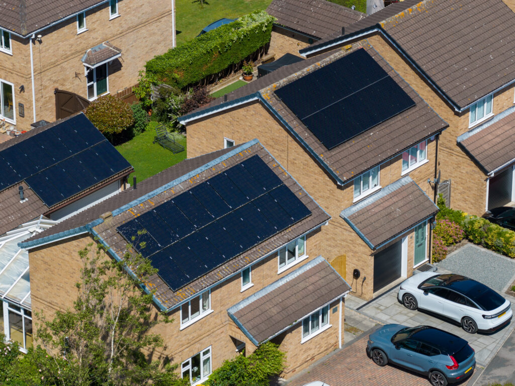 Aerial view of modern detached houses fitted with rooftop solar panels representing property managers moving to renewables