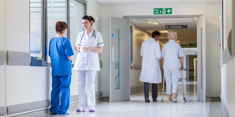 Hospital corridor with doctors, nurses & senior female patient Hospital corridor with doctors, nurses representing healthcare